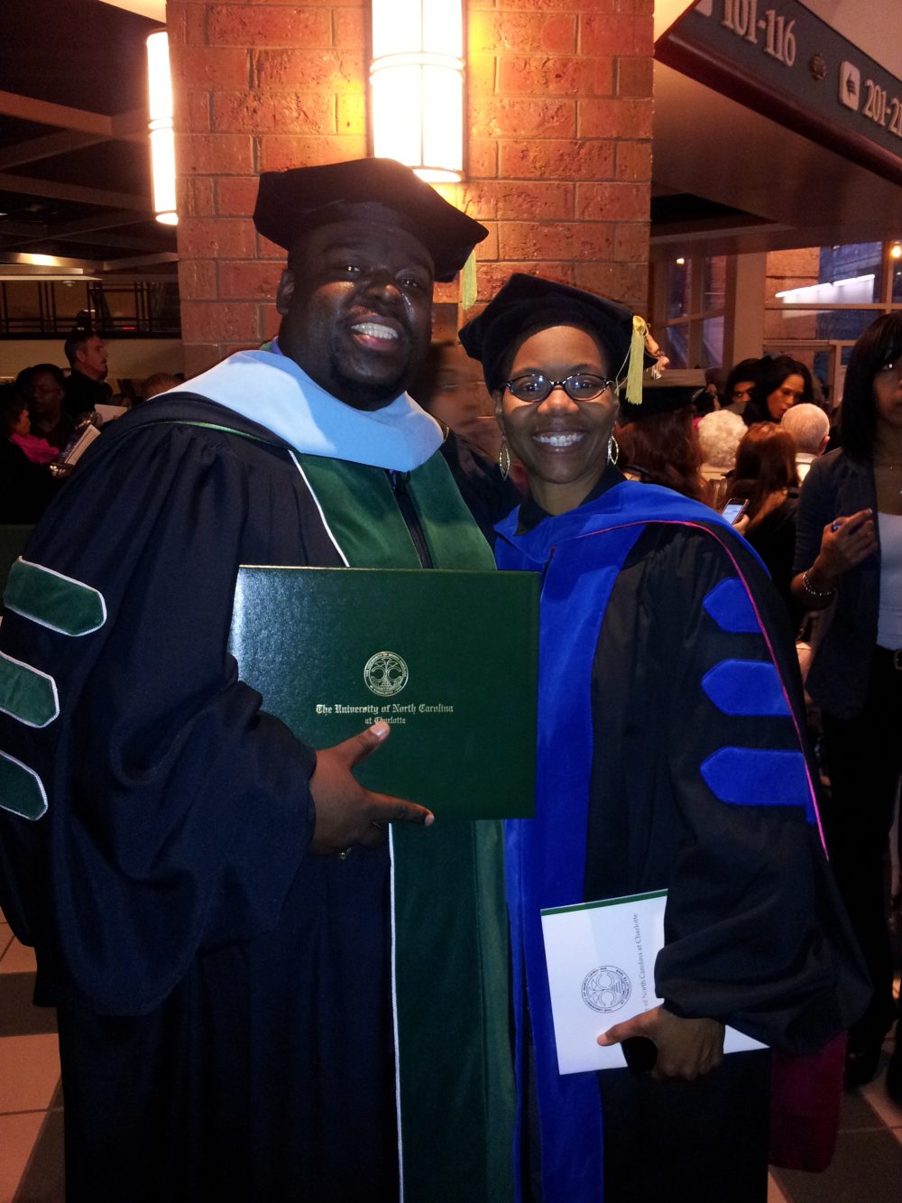 Wilson, diploma in hand, celebrating his doctoral hooding with mentor Merriweather